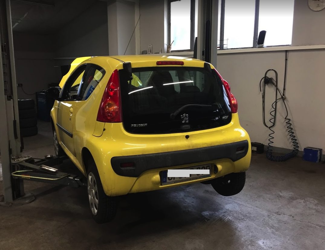 Gelber Kleinwagen auf der Hebebühne in der Werkstatt